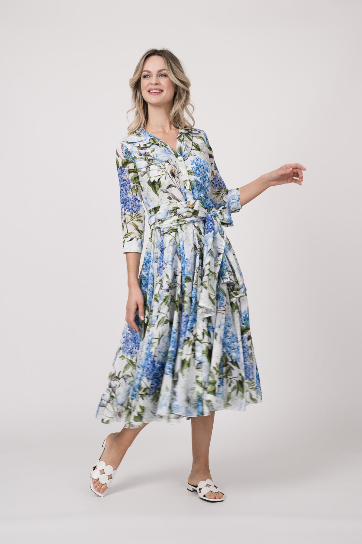 Model trägt ein langes Kleid der Marke Samantha Sung mit blauem, grünem und weißem Blumenmuster.
