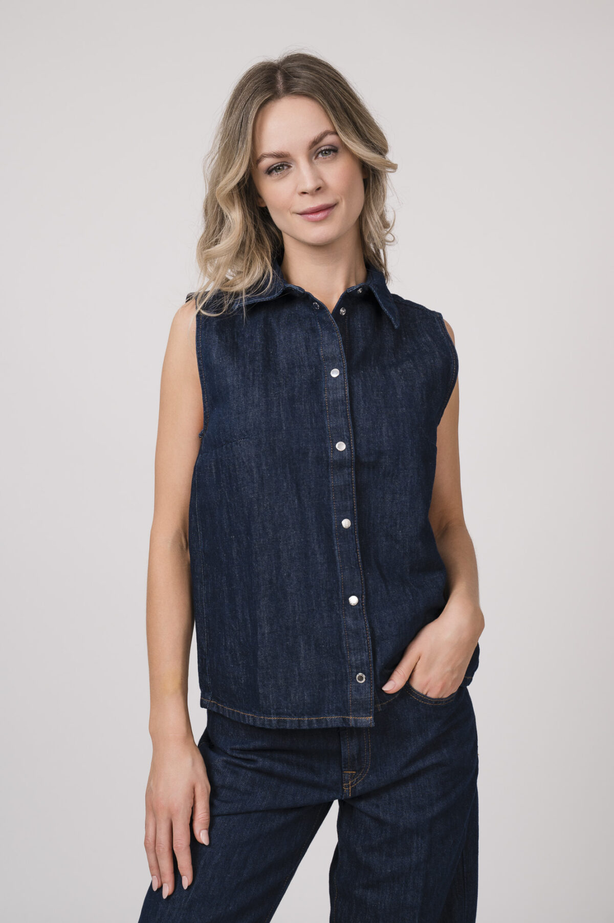 Model trägt eine dunkelblaue ärmellose Jeansbluse der Marke 7 for all mankind.