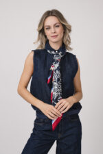 Model trägt eine dunkelblaue ärmellose Jeansbluse und Jeanshose der Marke 7 for all mankind und ein rot, weiß dunkelbalues Tuch von Joop! sowie einen dunkelblauen Gürtel von Aigner.