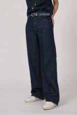 Model trägt eine dunkelblaue Jeanshose der Marke 7 for all mankind und einen dunkelblauen Gürtel von Aigner.