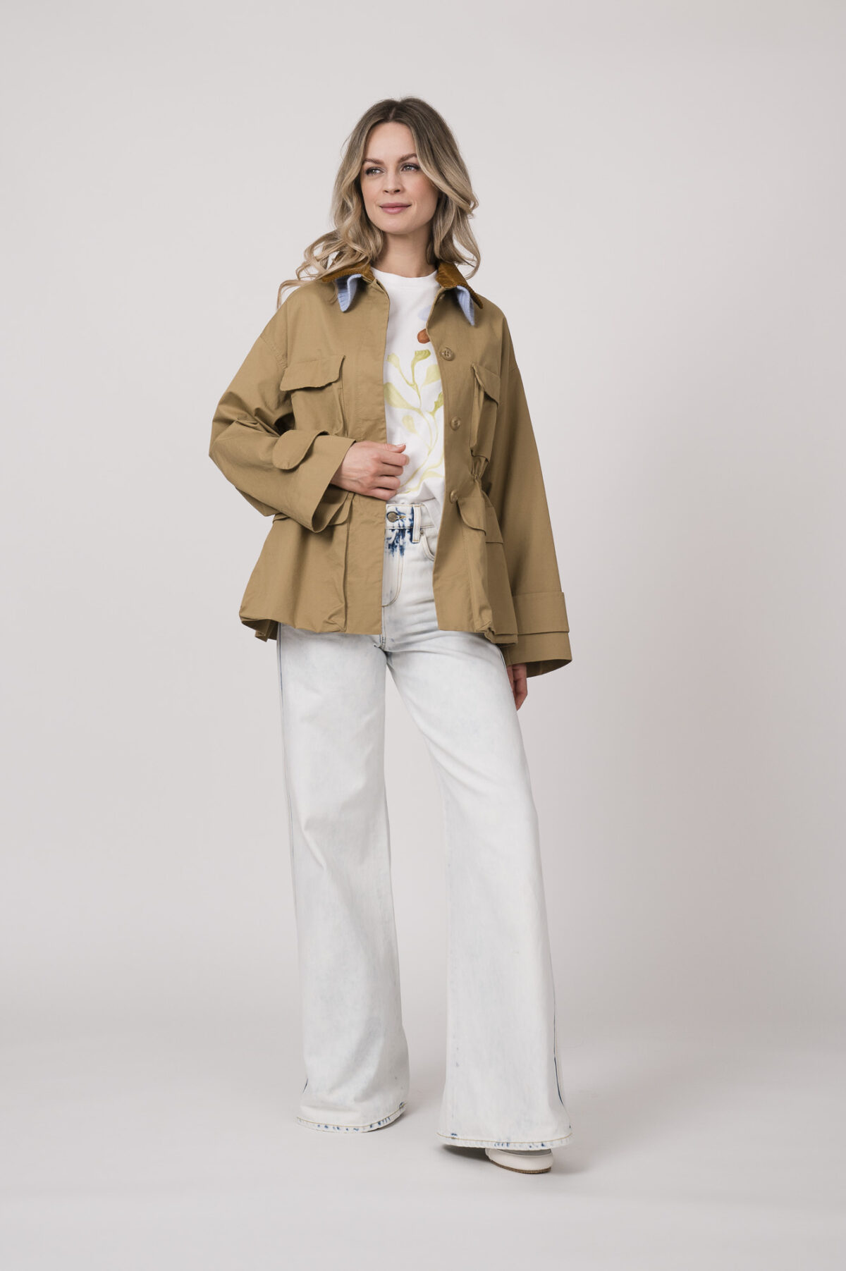 Model trägt eine beige Jacke der Marke Dorothee Schumacher mit hellblauem Strickkragen, ein helles Shirt der Marke Dorothee Schumacher und eine helle Jeans der Marek Dorothee Schumacher.
