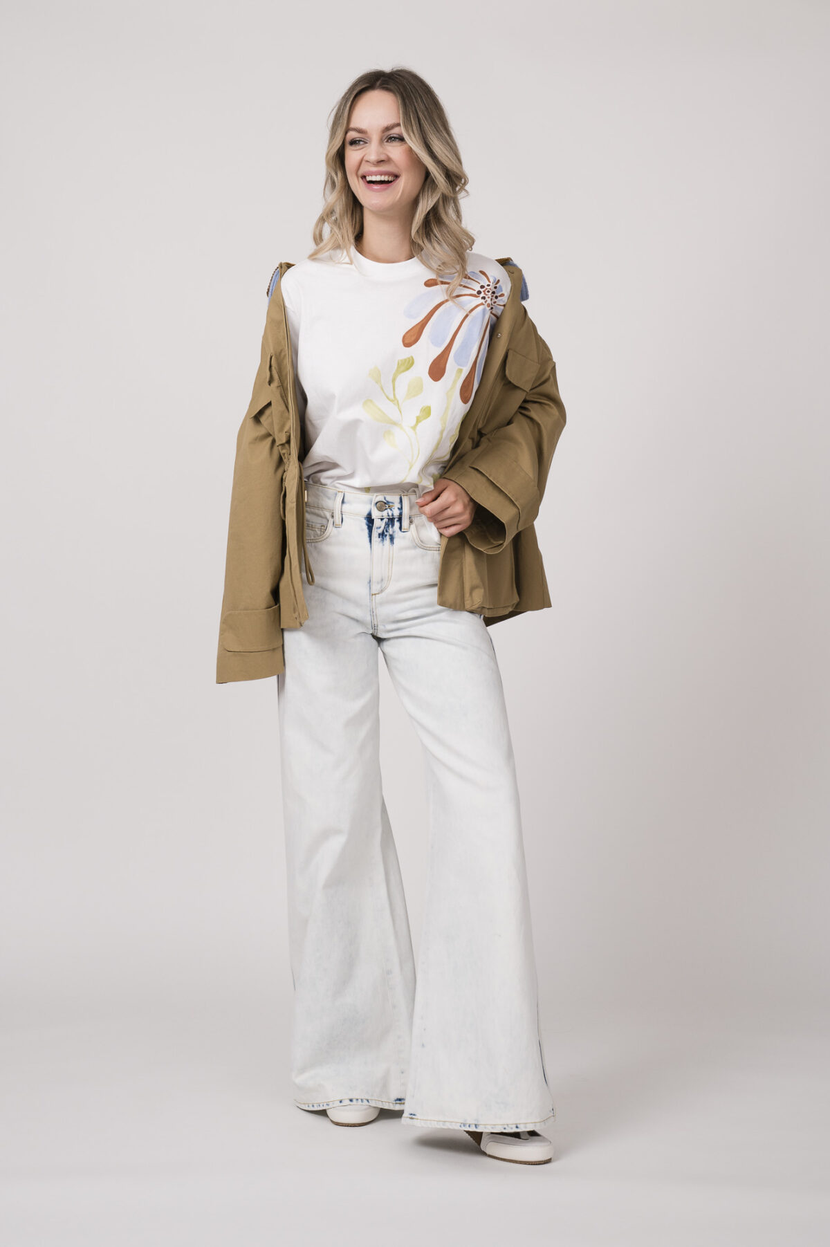 Model trägt eine beige Jacke der Marke Dorothee Schumacher mit hellblauem Strickkragen, ein helles Shirt der Marke Dorothee Schumacher und eine helle Jeans der Marek Dorothee Schumacher.