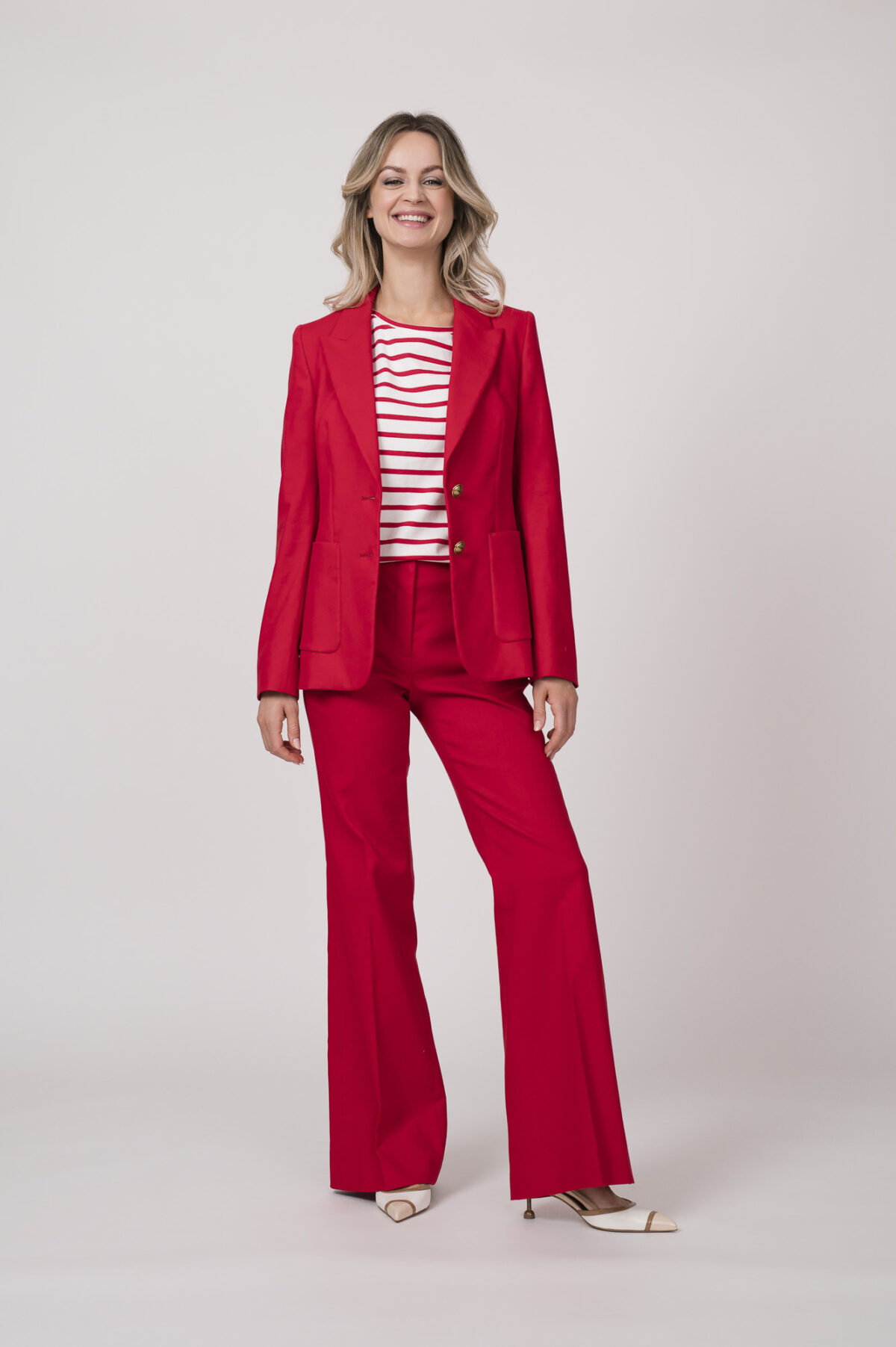 Model trägt einen roten Blazer, eine rote Hose und ein weiß-rot gestreiftes Shirt von Luisa Cerano.