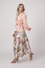 Model trägt einen pfirsich-farbigen Blazer von Marc Cain, ein natur-farbiges Top von Herzens und einen gemusterten Rock von Lunatica.