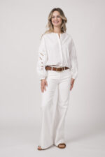 Model trägt eine weiße Bluse der Marke Dorothee Schumacher und eine weiße Jeans von True Religion. Der braue Gürtel ist von Dorothee Schumacher.