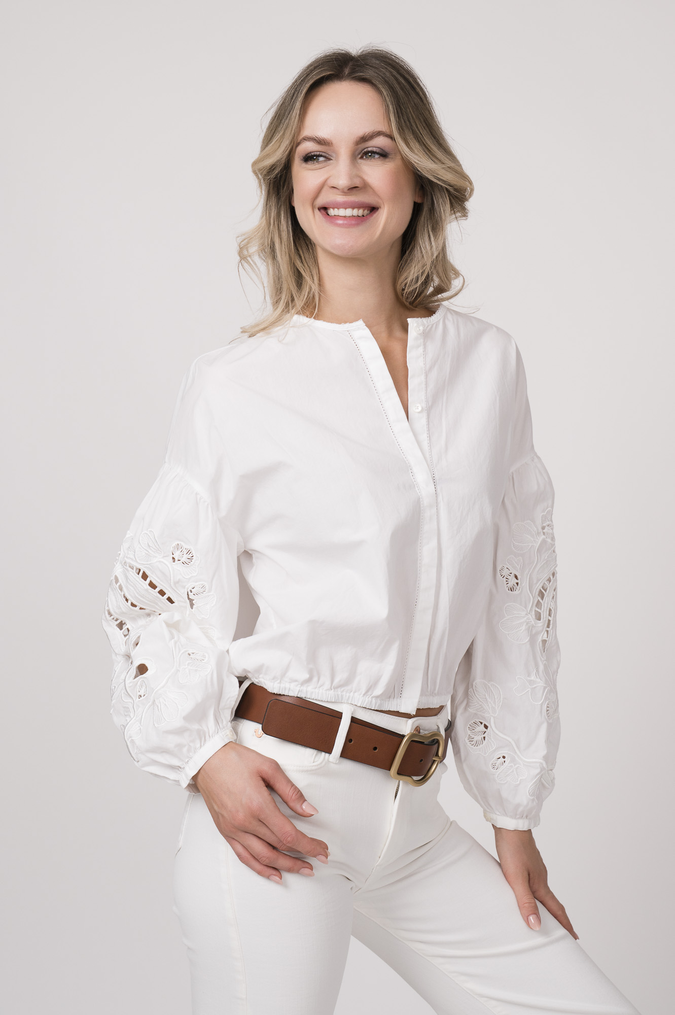 Model trägt eine weiße Bluse der Marke Dorothee Schumacher. Der braue Gürtel ist von Dorothee Schumacher.