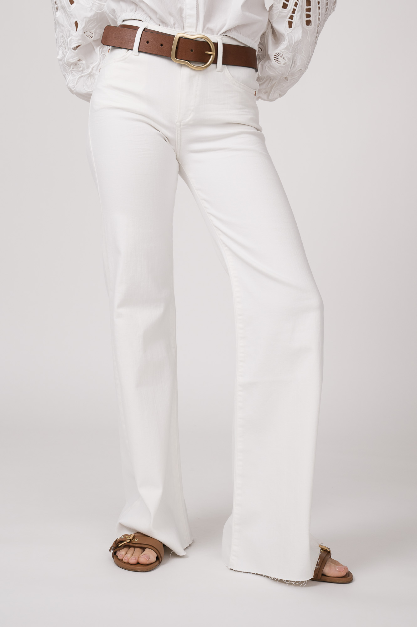 Model trägt eine weiße Jeans von True Religion. Der braue Gürtel ist von Dorothee Schumacher.