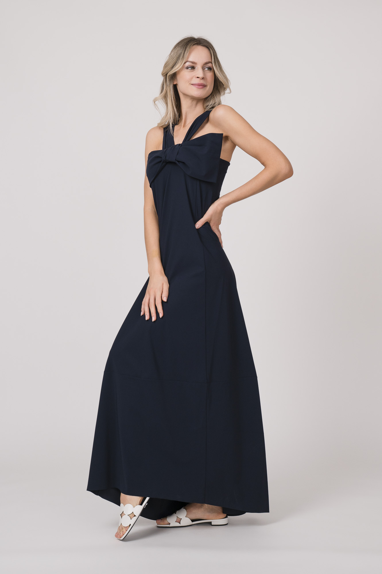 Model trägt ein marine-blaues Kleid mit Schleifendetail beim Dekolleté der Marke Dorothee Schumacher.