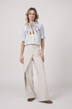 Model trägt eine hellblaue Bluse mit Blumenmuster der Marke Dorothee Schumacher und eine natur-weiße Hose der Marke Cambio.