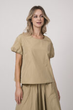 Model trägt einen beigen Rock, ein beiges Kurzarm-Oberteil der Marke Susanne Bommer