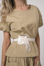 Model trägt einen beigen Rock, ein beiges Kurzarm-Oberteil und einen Federgürtel in weiß der Marke Susanne Bommer