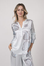 Model trägt eine fließende Bluse in hellem Blau mit Paisley Muster der Marke Herzens.