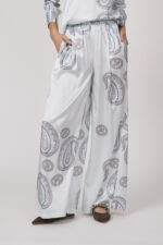 Model trägt eine fließende Hose in hellem Blau mit Paisley Muster der Marke Herzens.