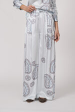 Model trägt eine fließende Hose in hellem Blau mit Paisley Muster der Marke Herzens.