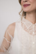 Model trägt ein Outfit der Marke Susanne Bommer in marine-blau bestehend aus: einem ärmellosem Seidentop, einer durchsichtige Tüllbluse.Model trägt ein Outfit der Marke Susanne Bommer in natur-weiß bestehend aus: einem ärmellosem Seidentop, einer durchsichtige Tüllbluse.