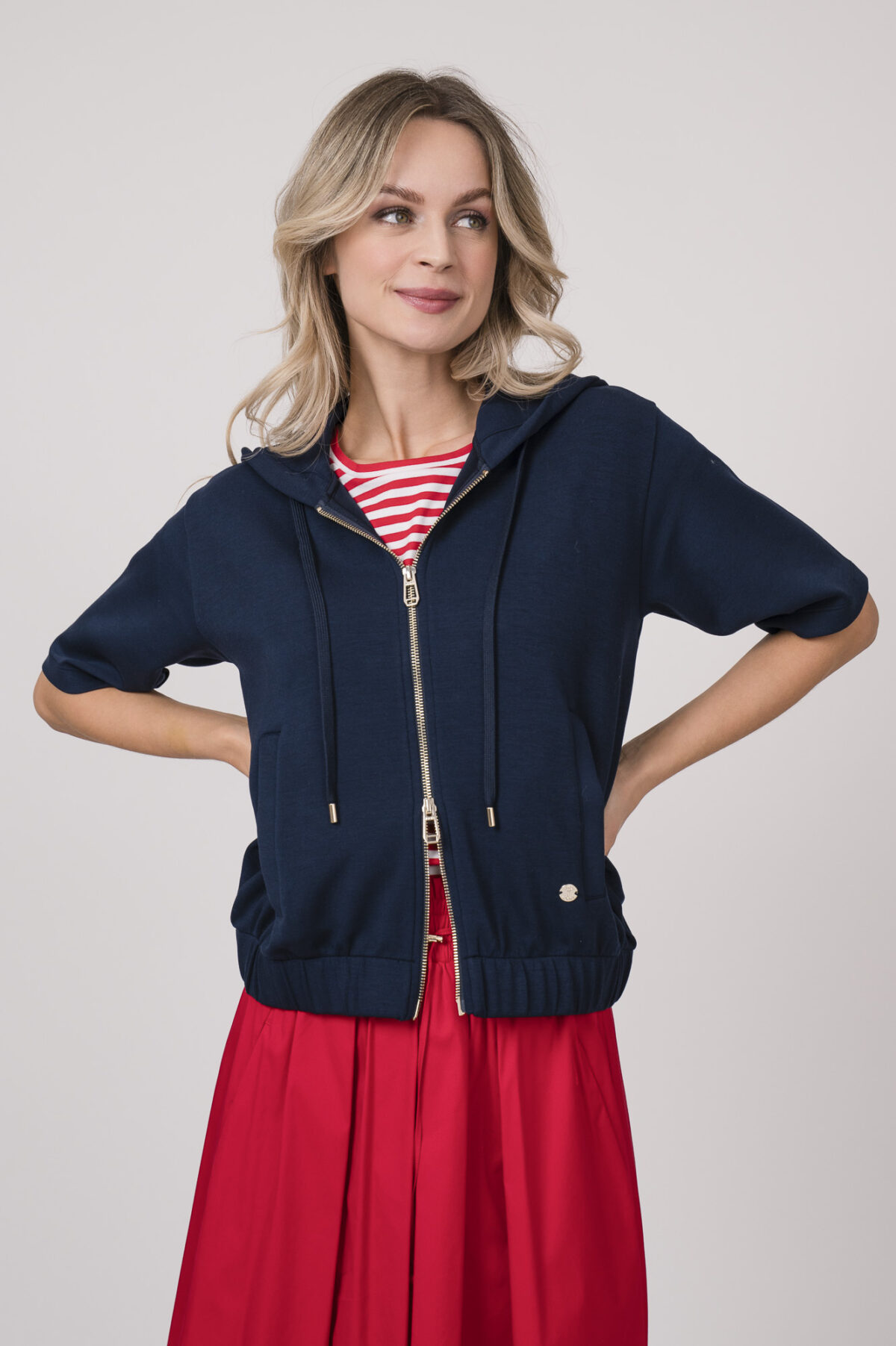 Model trägt einen dunkelblauen Kurzarm-Sweater mit Reißverschluss der Marke Joop! Und ein rot-weiß gestreiftes Shirt der Marke Joop!