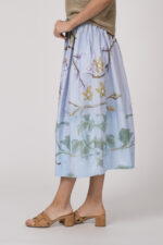 Model trägt einen hellblau gemusterten Rock der Marke Talking Walls.