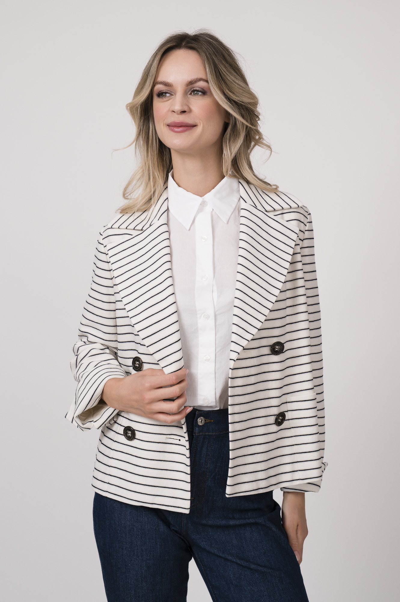 Model trägt eine weiß-dunkelblau gestreifte Blazerjacke der Marke Luisa Cerano, und eine weiße Bluse der Marke Rossana Diva.