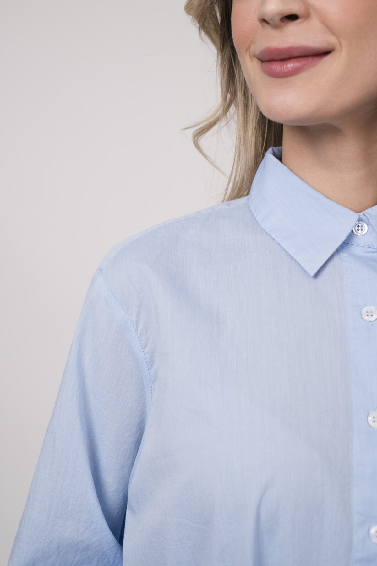 Model trägt eine hellblaue Bluse der Marke Rossana Diva.