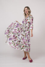 Model trägt ein helles Kleid mit floralem Muster der Marke Samantha Sung.