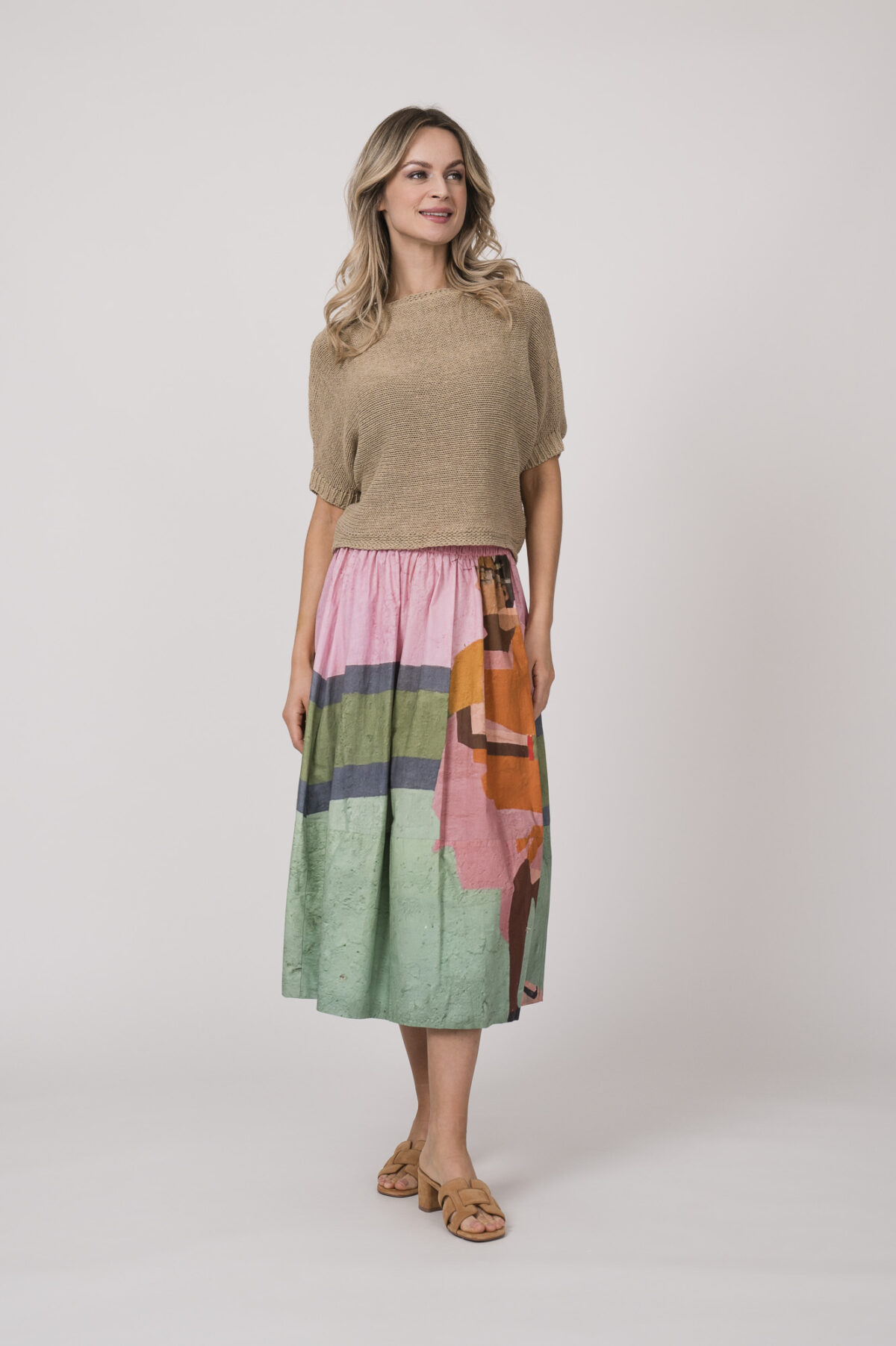 Model zeigt einen beigen Kurzarm-Pullover der Marke Talking Walls und einen bunt gemusterten Rock der Marke Talking Walls.