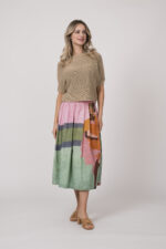 Model zeigt einen beigen Kurzarm-Pullover der Marke Talking Walls und einen bunt gemusterten Rock der Marke Talking Walls.