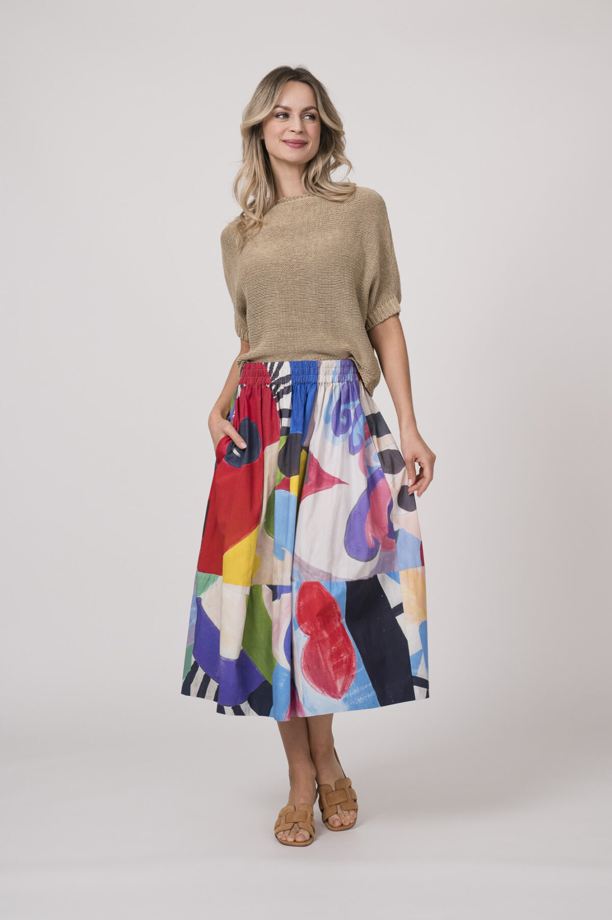 Model zeigt einen beigen Kurzarm-Pullover der Marke Talking Walls und einen bunten Rock der Marke Talking Walls.