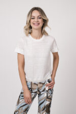 Model trägt ein Shirt der Marke Dorothee Schumacher in Weiß aus 100 % Hanf, dazu eine gemusterte Hose der Marke Cambio und einen Gürtel in Beige der Marke Aigner.