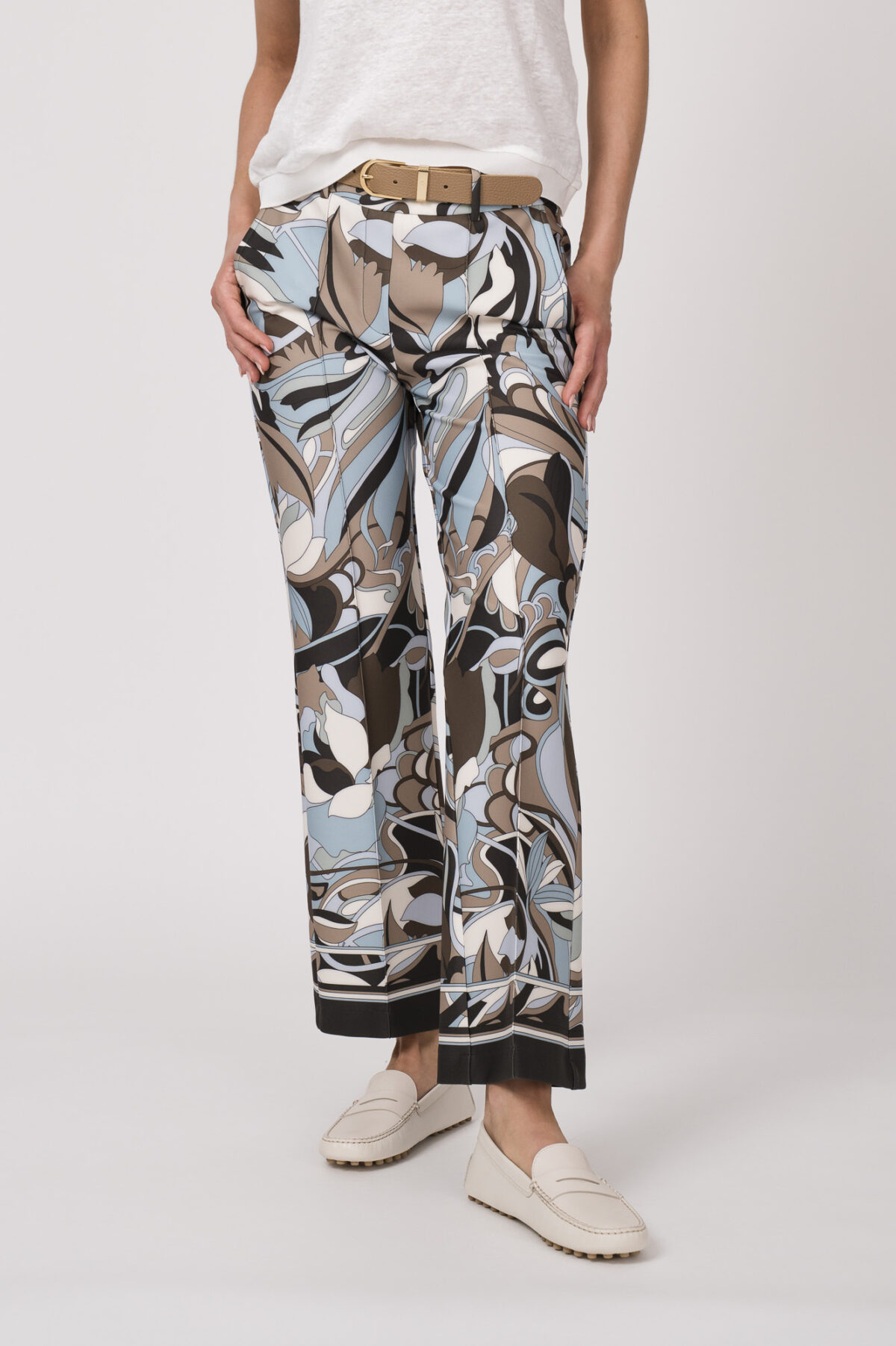 Model trägt ein Shirt der Marke Dorothee Schumacher in Weiß aus 100 % Hanf, dazu eine gemusterte Hose der Marke Cambio und einen Gürtel in Beige der Marke Aigner.