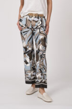 Model trägt ein Shirt der Marke Dorothee Schumacher in Weiß aus 100 % Hanf, dazu eine gemusterte Hose der Marke Cambio und einen Gürtel in Beige der Marke Aigner.