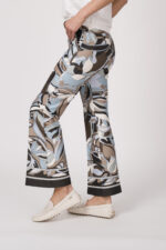 Model trägt ein Shirt der Marke Dorothee Schumacher in Weiß aus 100 % Hanf, dazu eine gemusterte Hose der Marke Cambio und einen Gürtel in Beige der Marke Aigner.