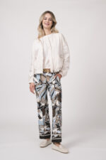 Model trägt eine Jacke der Marke Lis Lareida in Natur, ein Shirt der Marke Dorothee Schumacher in Weiß aus 100 % Hanf, dazu eine gemusterte Hose der Marke Cambio und einen Gürtel in Beige der Marke Aigner.