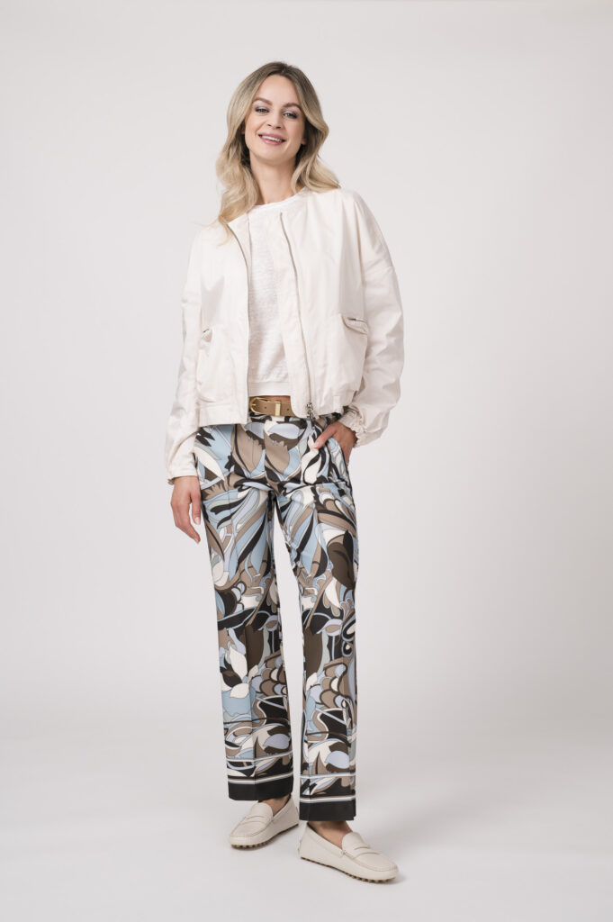 Model trägt eine Jacke der Marke Lis Lareida in Natur, ein Shirt der Marke Dorothee Schumacher in Weiß aus 100 % Hanf, dazu eine gemusterte Hose der Marke Cambio und einen Gürtel in Beige der Marke Aigner.