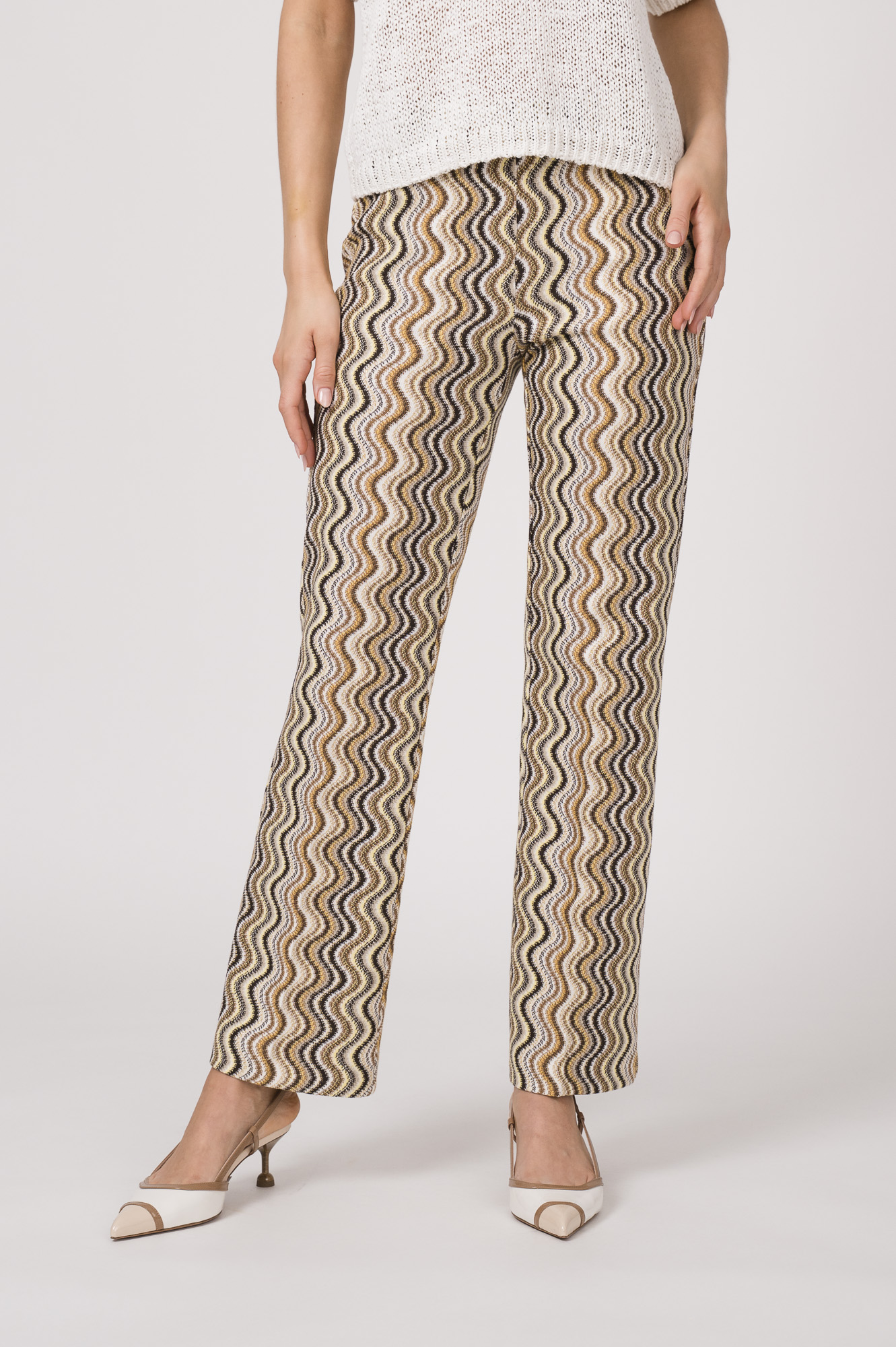 Model trägt eine gemusterte Hose der Marke Cambio, dazu einen Kurzarmpullover der Marke FFC in Weiß.