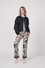 Model trägt eine Jacke der Marke Lis Lareida in Marine, ein Shirt der Marke Dorothee Schumacher in Hellblau aus 100 % Hanf, dazu eine gemusterte Hose der Marke Cambio und einen Gürtel in Beige der Marke Aigner.