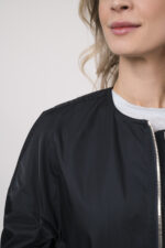 Model trägt eine Jacke der Marke Lis Lareida in Marine, ein Shirt der Marke Dorothee Schumacher in Hellblau aus 100 % Hanf, dazu eine gemusterte Hose der Marke Cambio und einen Gürtel in Beige der Marke Aigner.