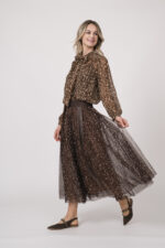 Model trägt eine Bluse mit Schnuppe der Marke Joop! und einen dazu passenden Plisseerock der Marke Joop!. Beides in einem Leo-Muster.