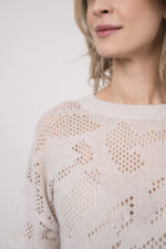 Model trägt einen Langarmpullover in der Farbe Sand der Marke Herzens, dazu einen Rock der Marke FFC in Hellblau.