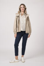 Model trägt eine Jacke der Marke Duno in der Farbe Sand. Eine Bluse der Marke Rossana Diva mit Blumenmuster. Dazu eine Hose der Marke Mason's in Marine.