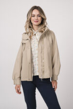 Model trägt eine Jacke der Marke Duno in der Farbe Sand. Eine Bluse der Marke Rossana Diva mit Blumenmuster. Dazu eine Hose der Marke Mason's in Marine.