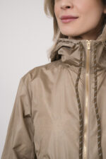 Model trägt eine Jacke der Marke Lis Lareida in der Farbe Sand. Eine Bluse der Marke Rossana Diva mit Blumenmuster. Dazu eine Hose der Marke Mason's in Marine.