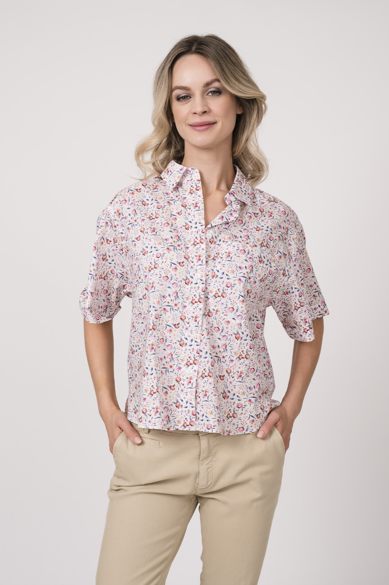 Model trägt eine Bluse der Marke Rossana Diva mit Blumenmuster. Dazu eine Hose der Marke Mason's in der Farbe Sand.