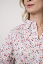 Model trägt eine Bluse der Marke Rossana Diva mit Blumenmuster. Dazu eine Hose der Marke Mason's in der Farbe Sand.