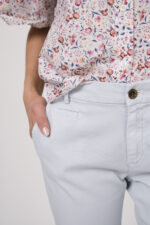 Model trägt eine Bluse der Marke Rossana Diva mit Blumenmuster, dazu eine Hose der Marke Mason's in Hellblau.