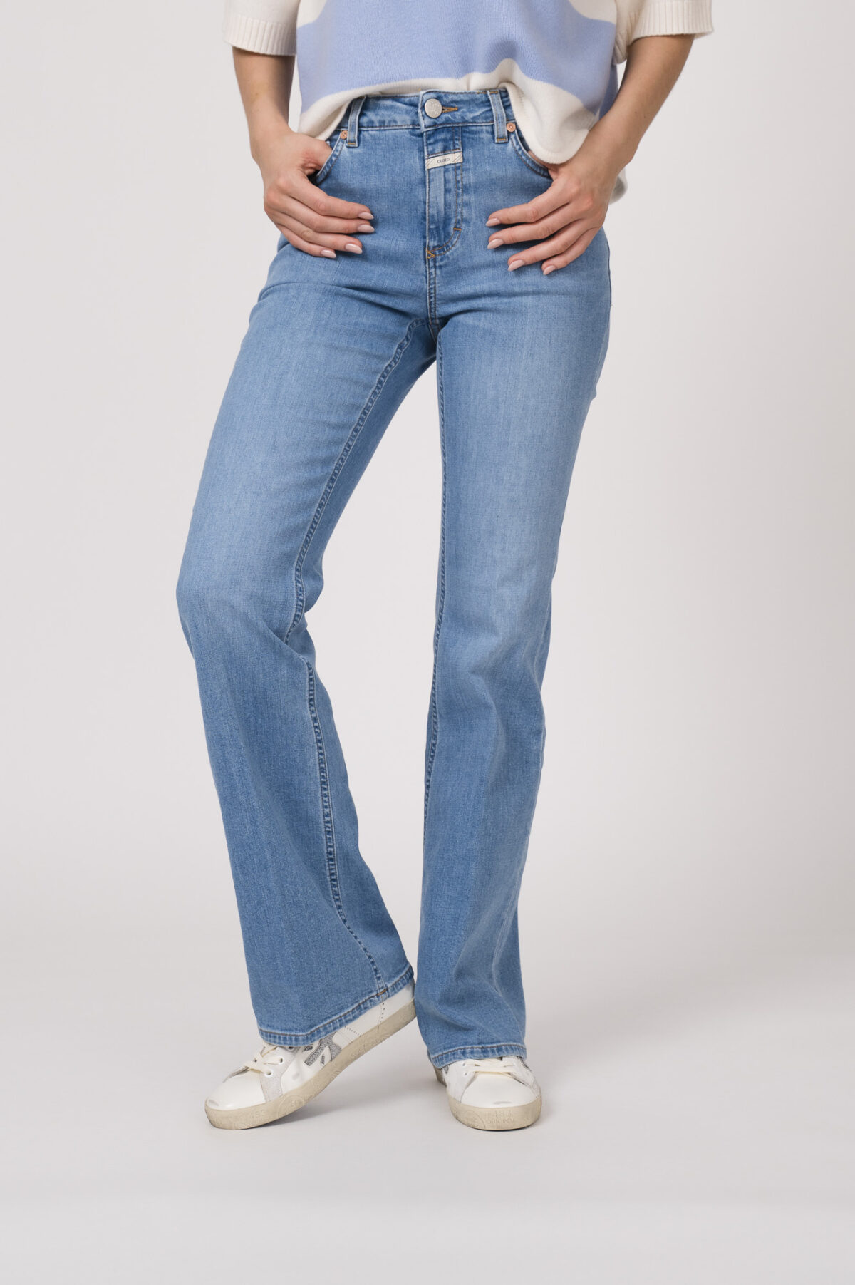 Model trägt einen blau-weiß gestreiften Pullover der Marke Dorothee Schumacher, dazu eine Jeans der Marke Closed in hellblau.