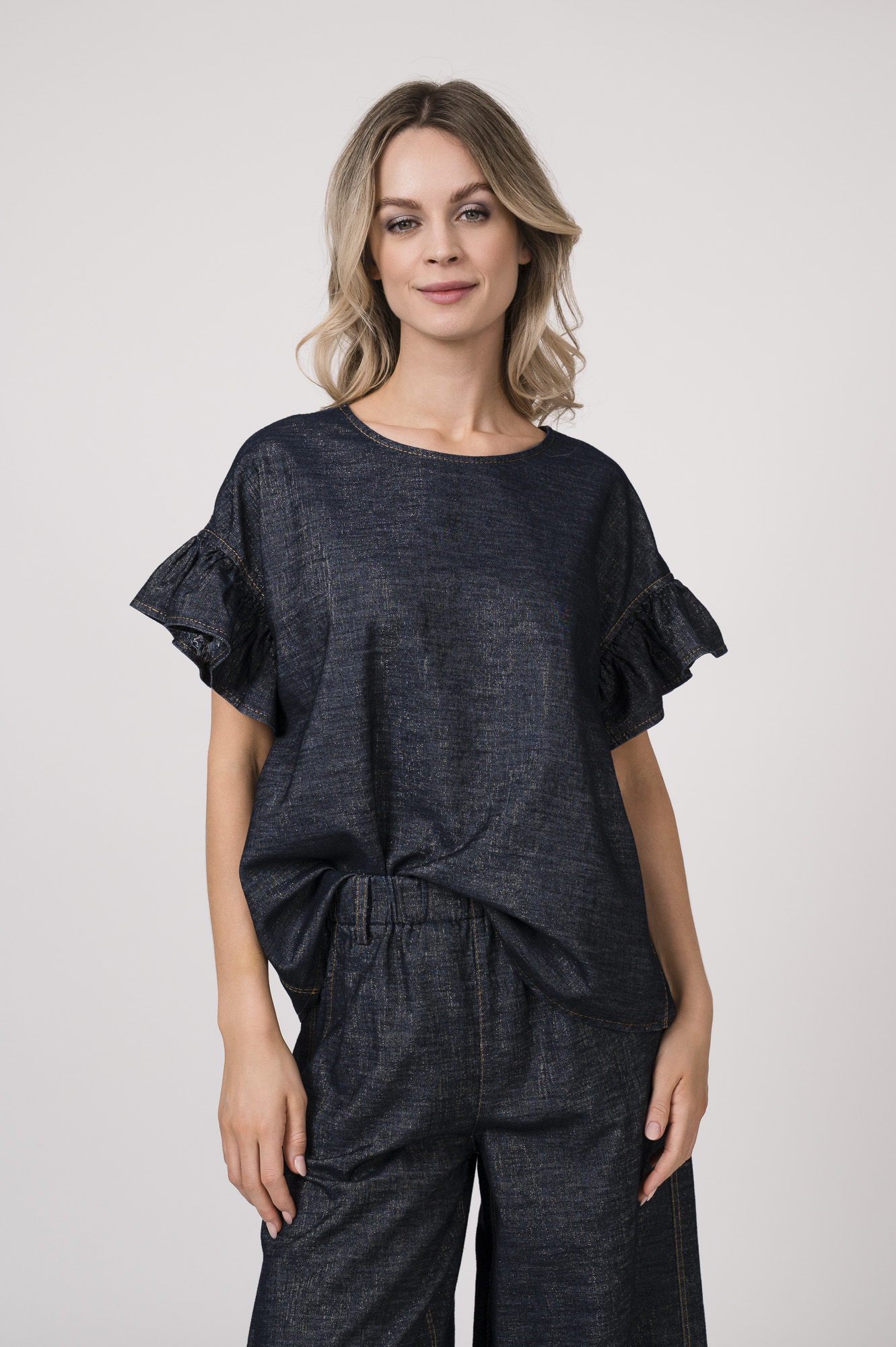 Model trägt ein denim Kurzarmshirt der Marke Susanne Bommer, dazu die passenden Jeans der Marke Susanne Bommer.