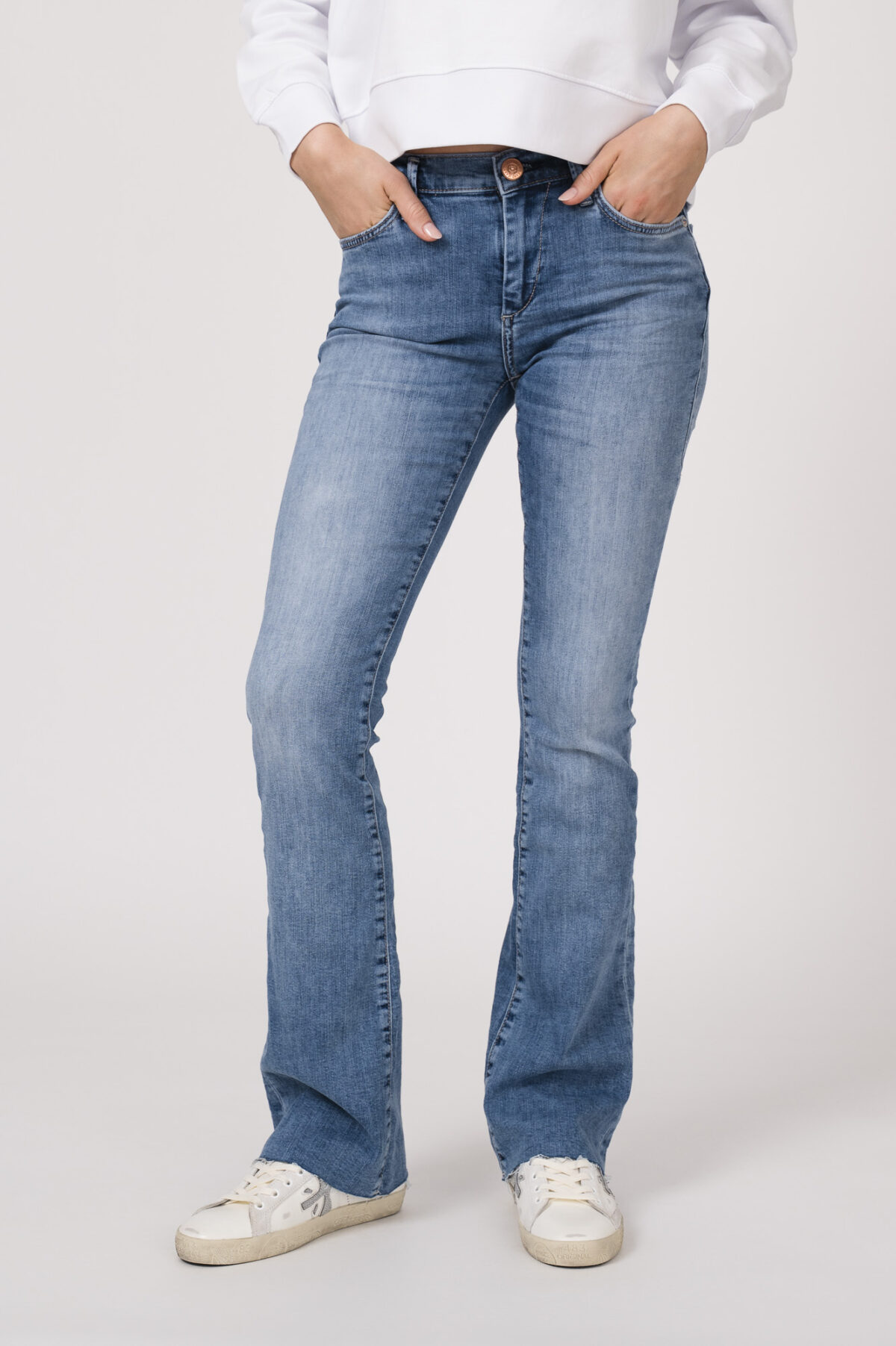 Model trägt einen Lounge-Sweater der Marke Sustyle in Weiß mit Motiv in Pink auf der Vorderseite. Dazu eine Jeans der Marke True Religion in Mittelblau.