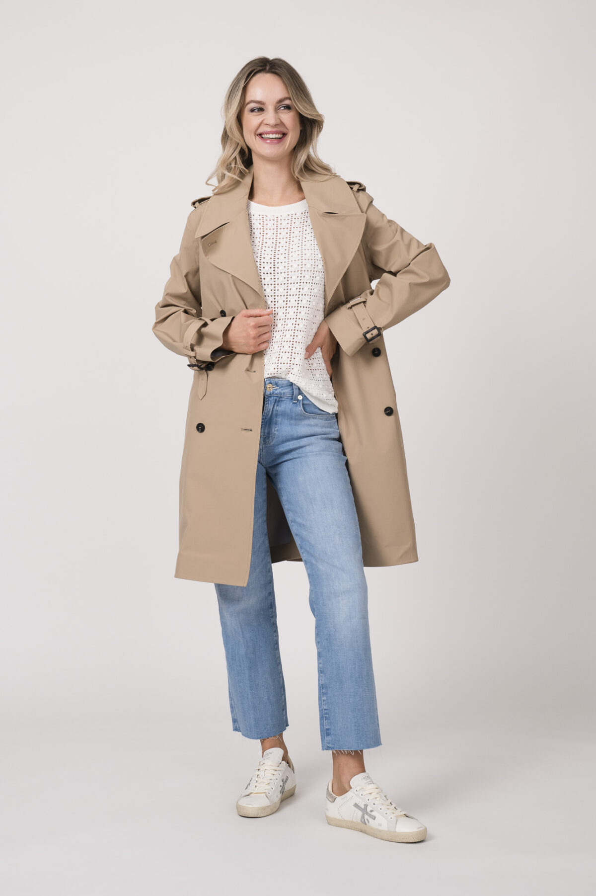 Model trägt einen Kurzarmpulli der Marke Joop! in Weiß, eine Jeans der Marke 7 for all mankind in hellblau, einen Mantel der Marke Save the Duck in Camel.