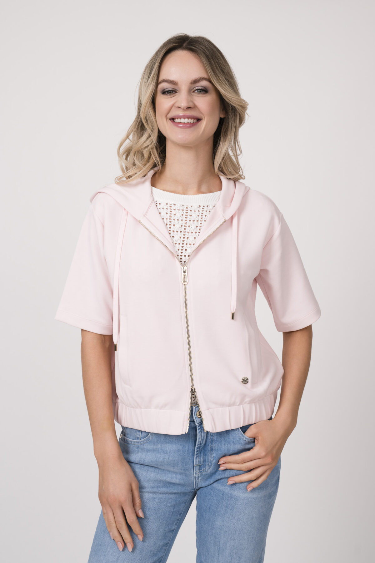 Model trägt einen Kurzarmpulli der Marke Joop! in Weiß, eine Jeans der Marke 7 for all mankind in hellblau, einen Lounge Sweater der Marke Joop! in Rosa.