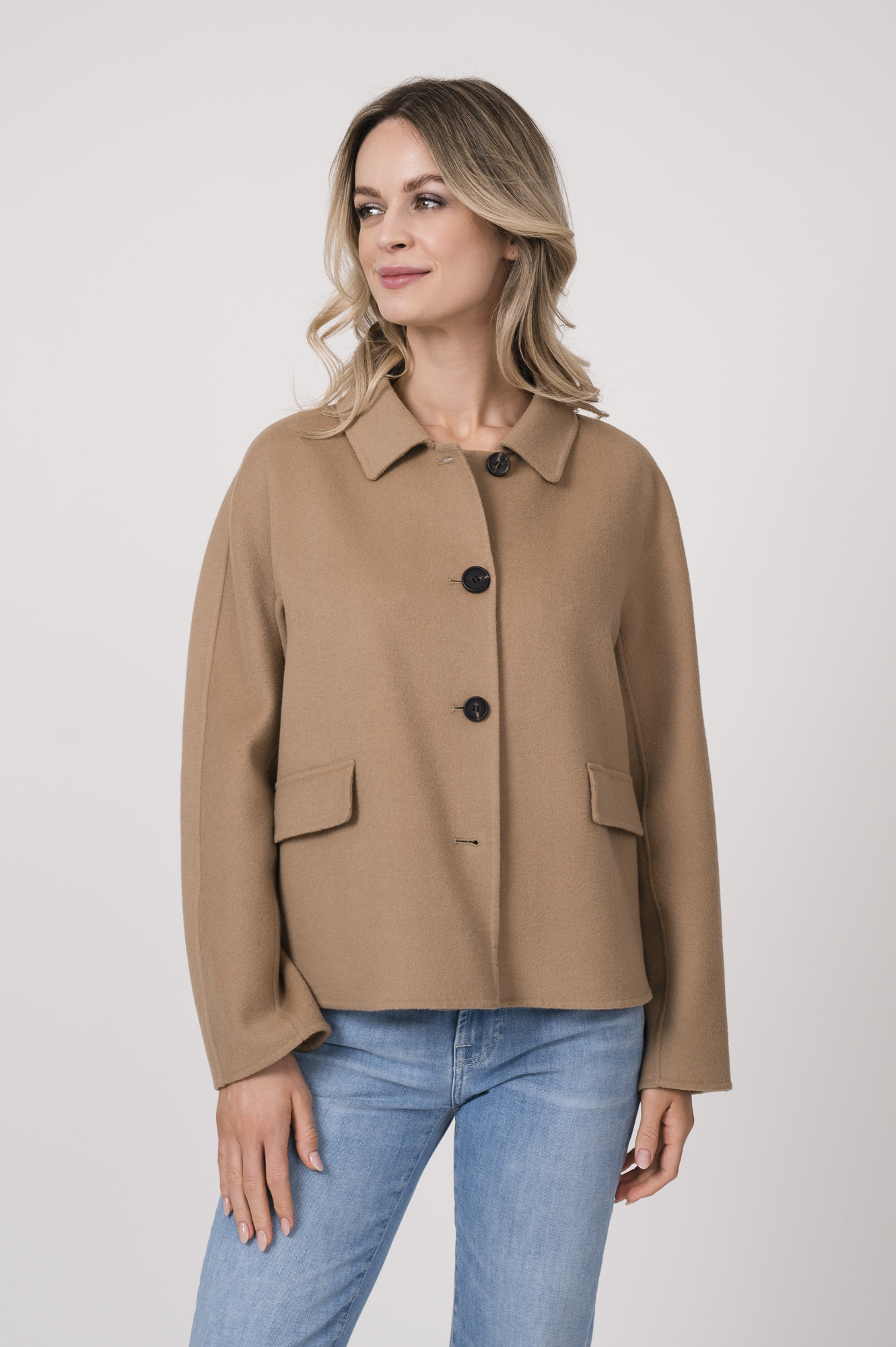 Model trägt einen Kurzarmpulli der Marke Joop! in Weiß, eine Jeans der Marke 7 for all mankind in hellblau. Eine Jacke der Merke Mabrun in Camel.